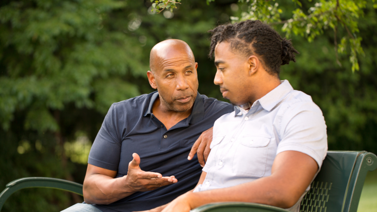 Mentor masculino y aprendiz masculino sentados afuera en un parque