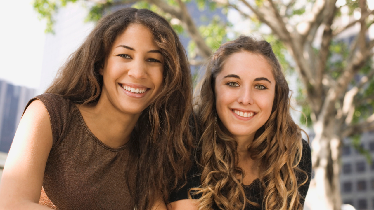 Two young girls sitting outside and smiling