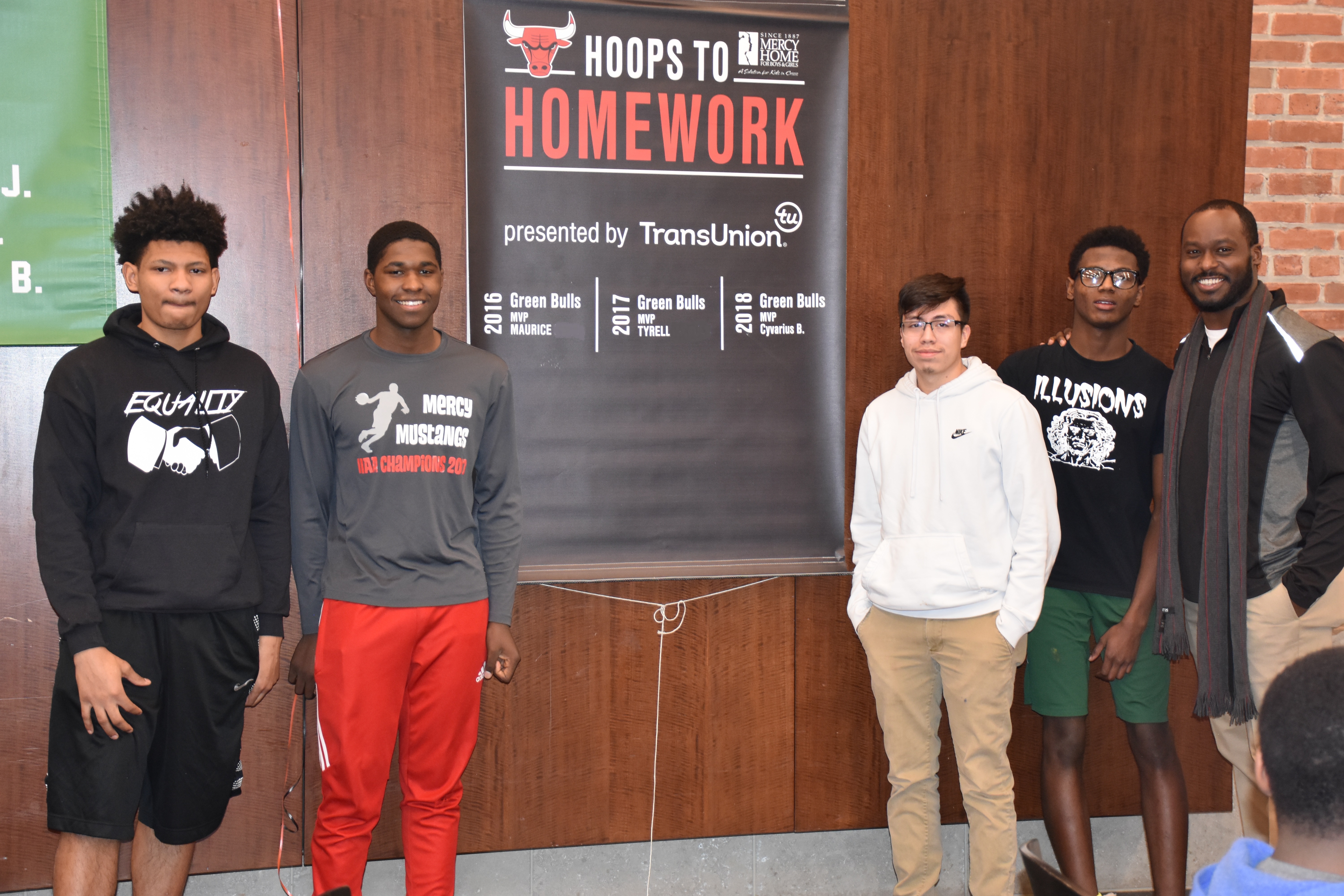 Mercy Home youth standing by hoops to homework banner