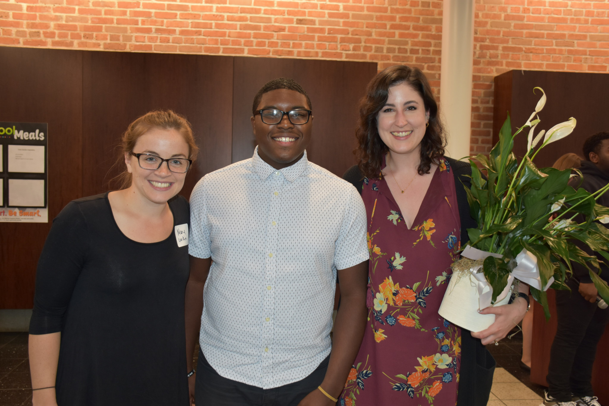 Two young women and one young man smiling at employer appreciation dinner