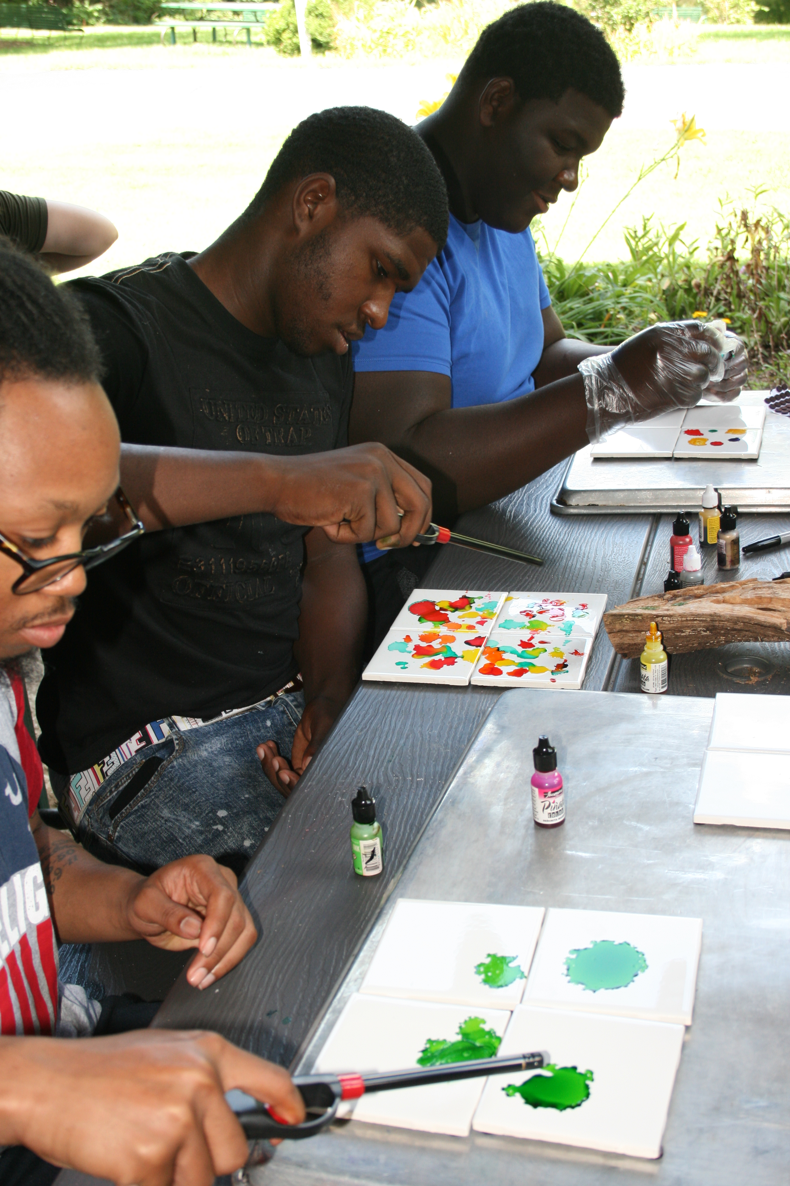 Three young men working on watercolor painting at AfterCare Scholar Retreat