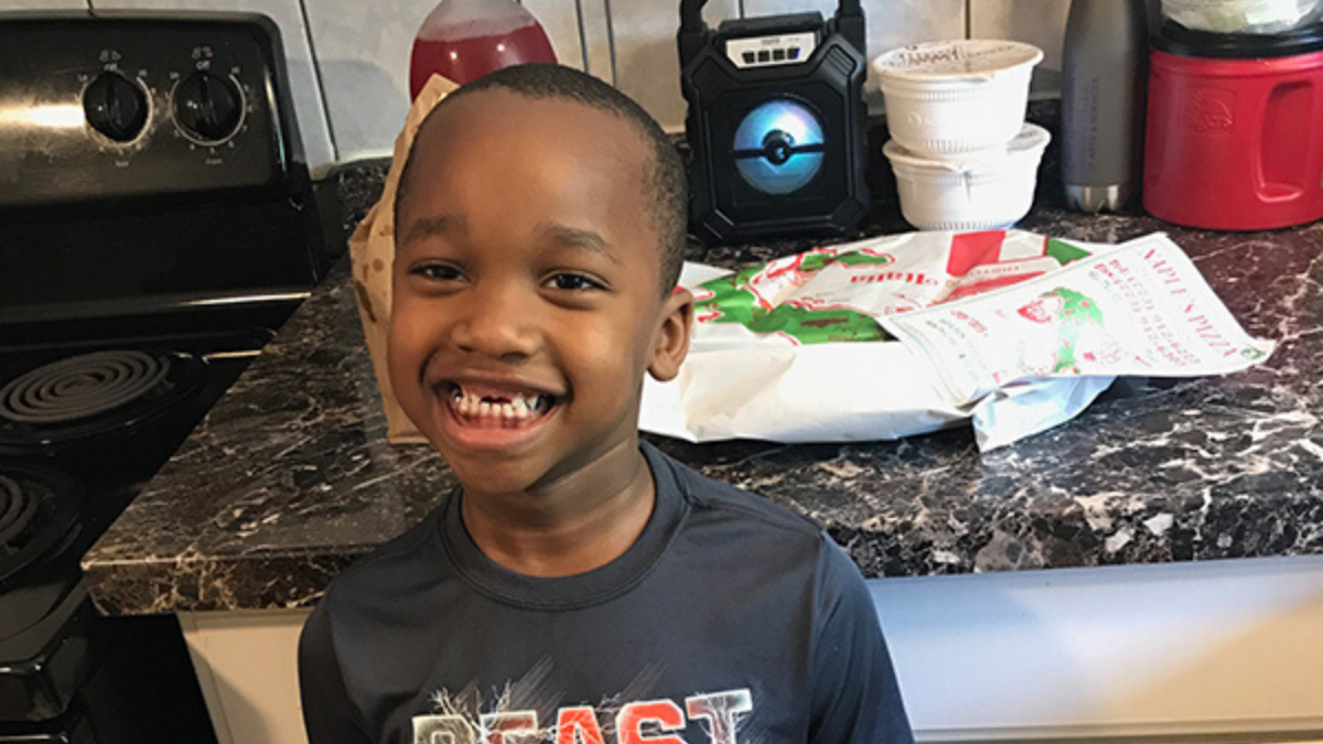 young boy smiling with pizza