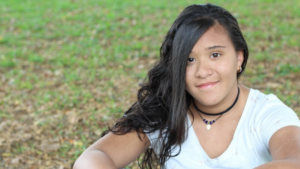 Girl sitting in grass and smiling