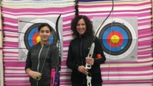 Young woman and mentor practice archery