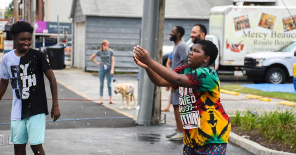 One of the boys reaches out his hands to catch a water balloon.