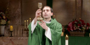 Fr. James Wallace raises a chalice while he prepares the communion for the Sunday Mass at Mercy Home community.