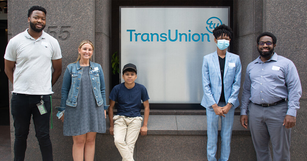 Some of Mercy Home's kids and youth care workers stand in front the TransUnion sign. 