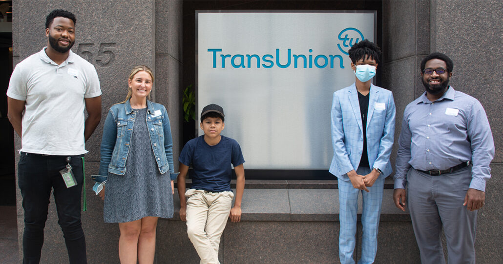 Some of Mercy Home's kids and youth care workers stand in front the TransUnion sign.