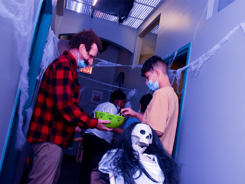 A Mercy Home kid reaches for a piece of candy from a costumed coworker. 