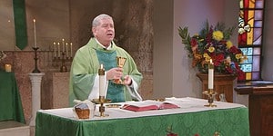 Fr. Scott Donahue raises a cup to bless it as he prepares Communion