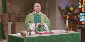 Fr. Scot Donahue holds his hands prayerfully as he speaks to the Sunday Mass community.