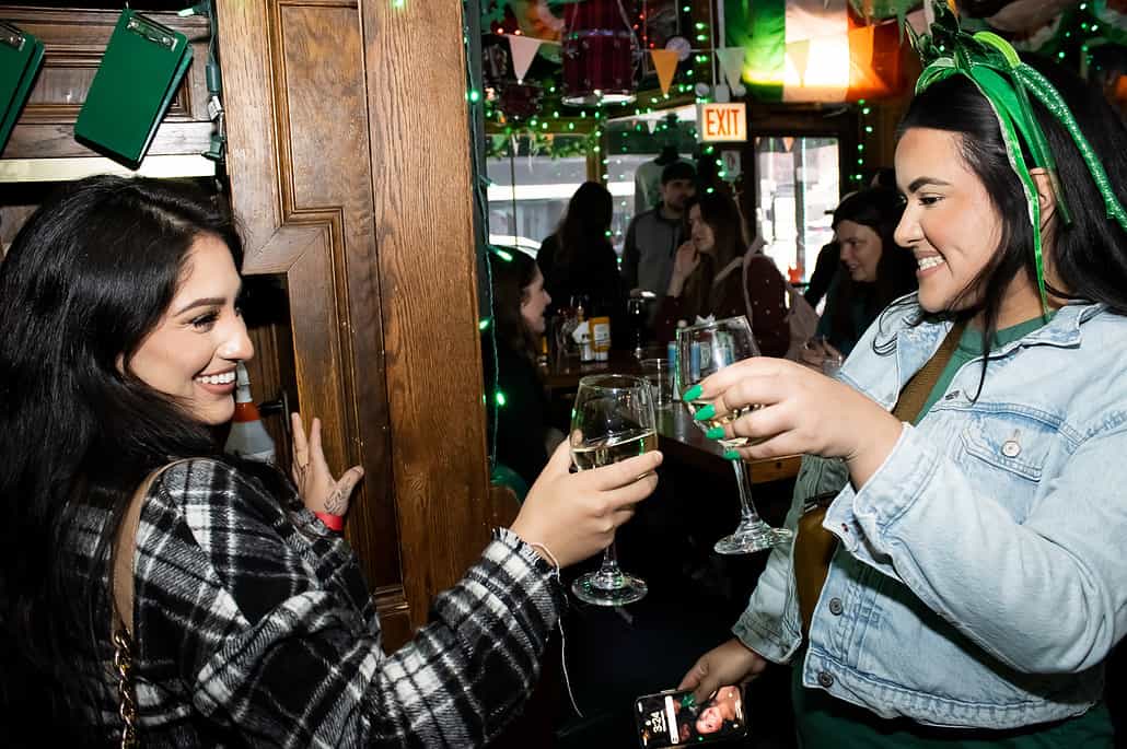 Two women standing clinking beverage in an Irish Pub Butch McGuires