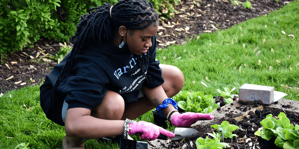 Una niña de Mercy Home palpa la tierra para asegurar una nueva adición al jardín.