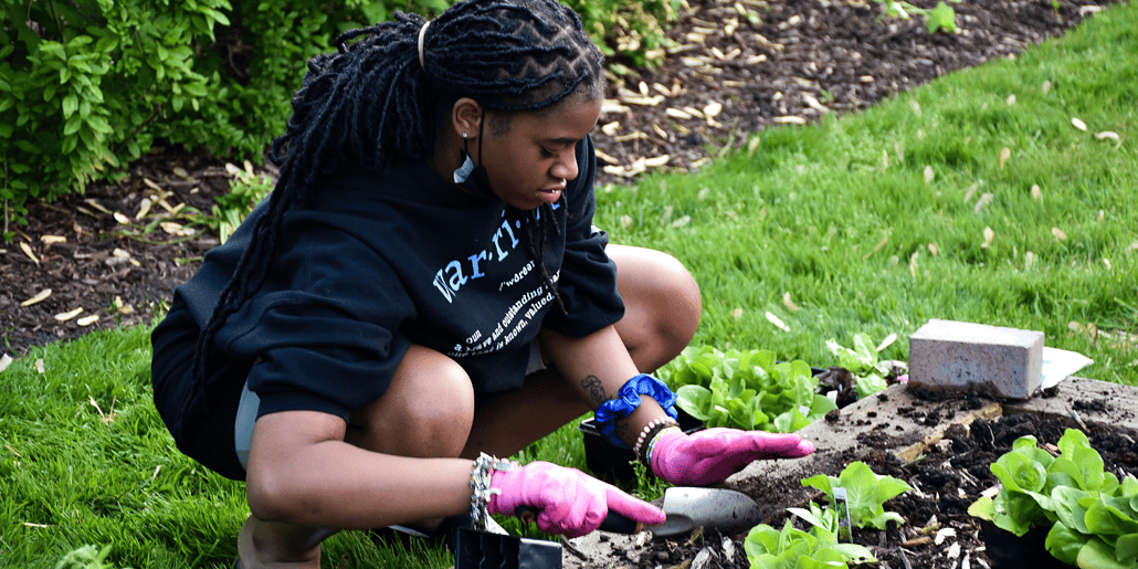 A Mercy Home girl pats down the soil to secure a new addition to the garden.