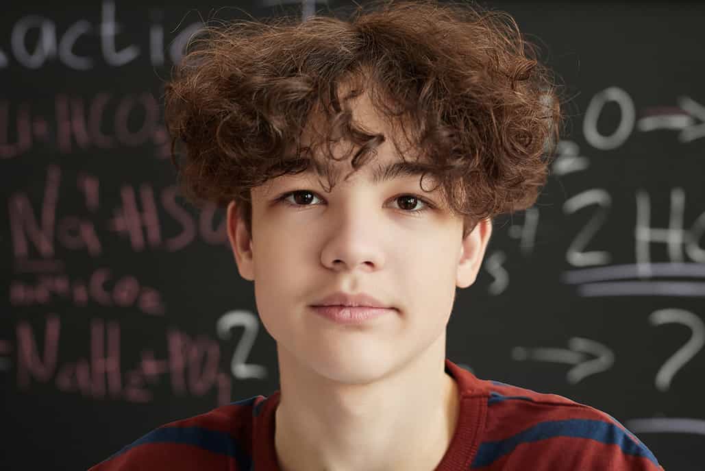 Close-up Vertical Portrait of a teenage boy, Alex, wearing a red and blue striped shirt and looking at the camera looking sad