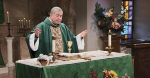 Fr. Scott Donahue raises his hands to bless this week's communion as he leads the Sunday Mass community at Mercy Home in celebration of the Nineteenth Sunday in Ordinary Time.