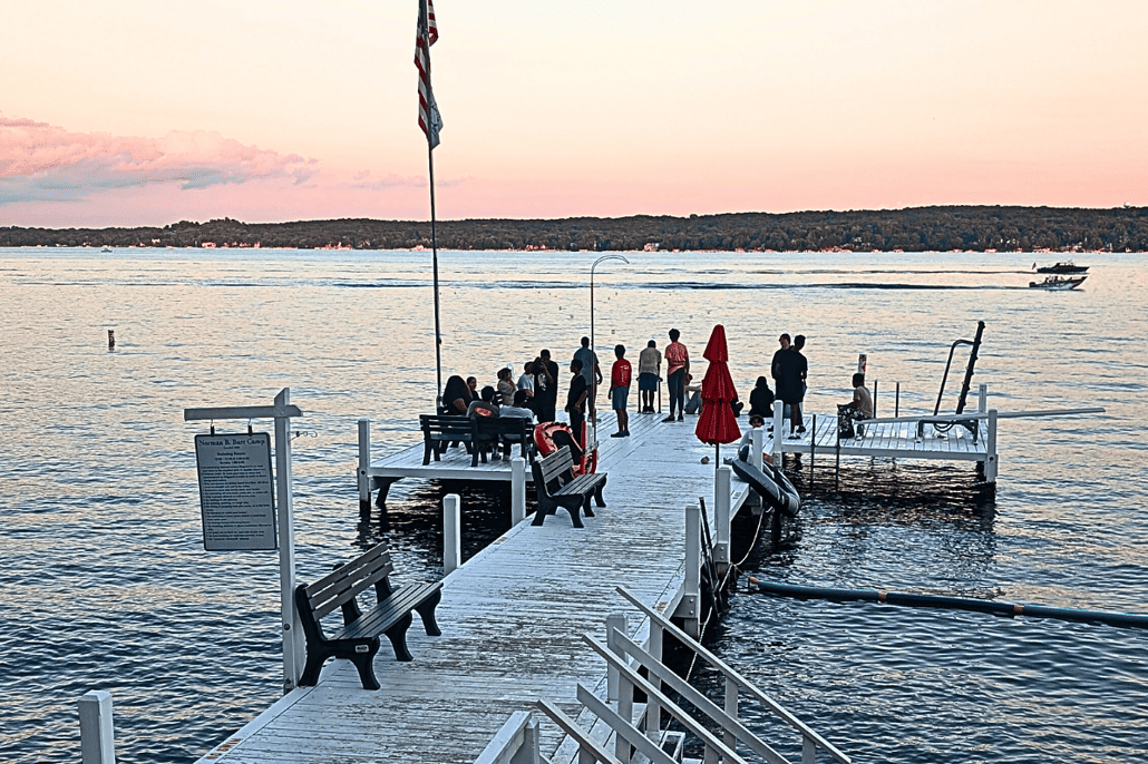 A group of youth and staff gather on the pier at the lake.
