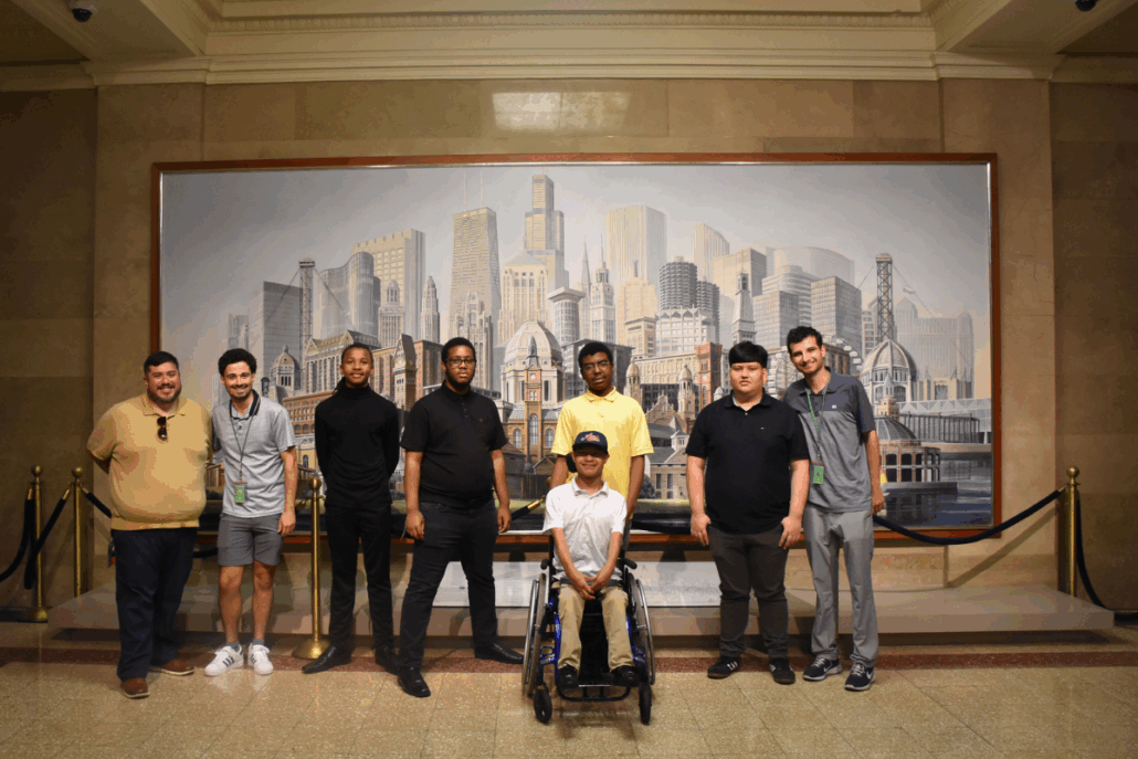 A group stands in front of a large art piece depicting Chicago's skyline.